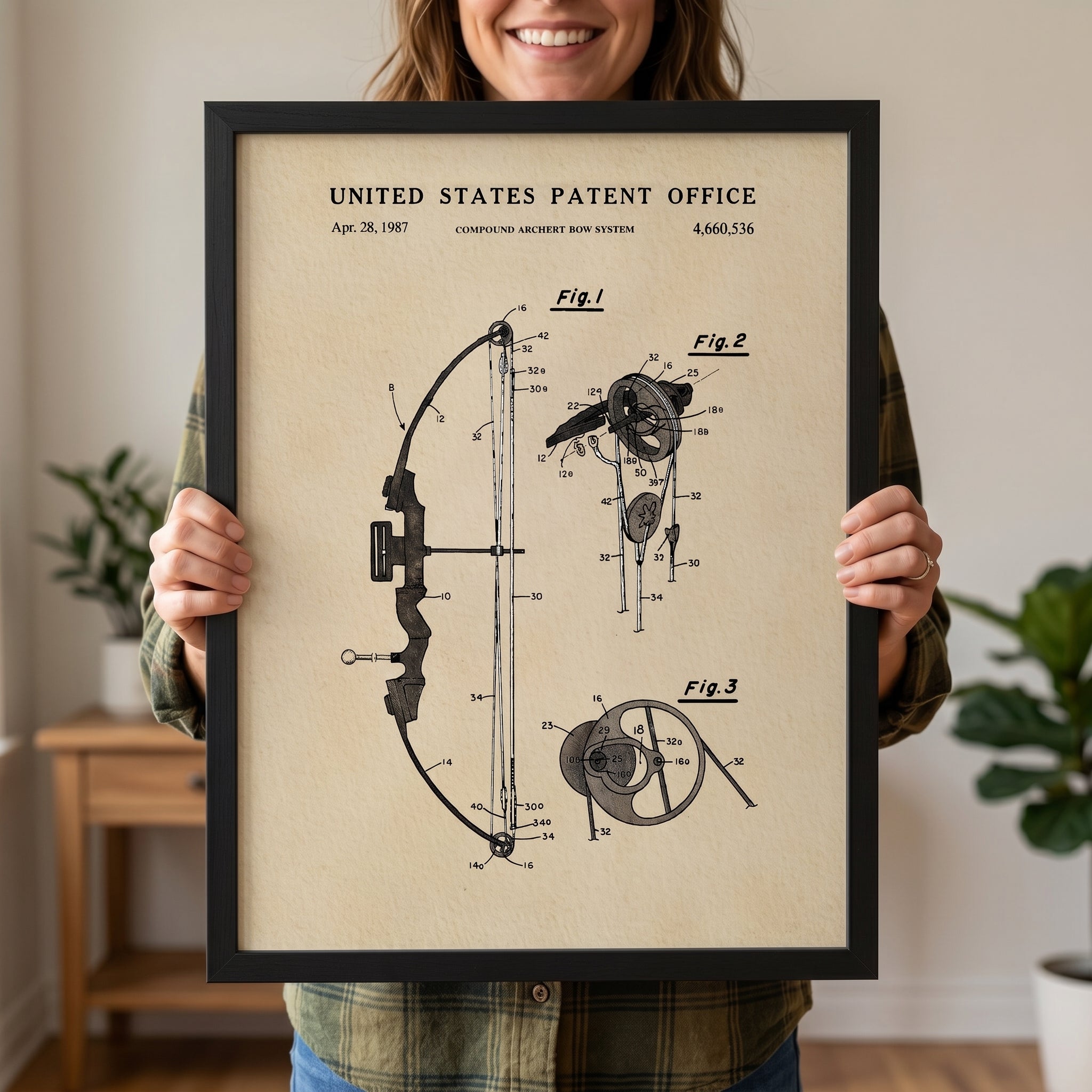 Woman holding a framed Compound Bow patent print with vintage watercolor artwork