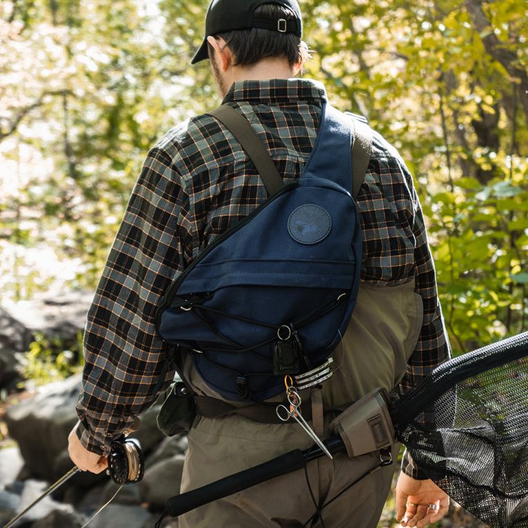 Hiker wearing the Duluth Pack 16L Canvas Sling Pack on the trail