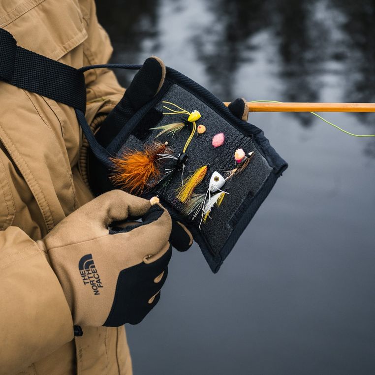 Angler using a Duluth Pack Bi-Fold Fly Wallet to organize and change flies