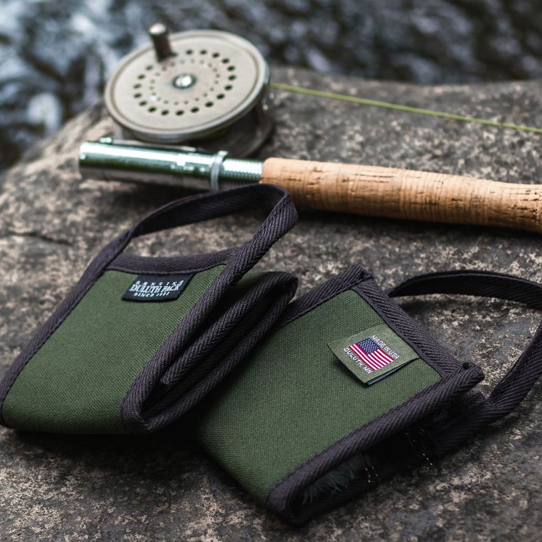 Duluth Pack Bi-Fold Fly Wallet beside a fly fishing rod