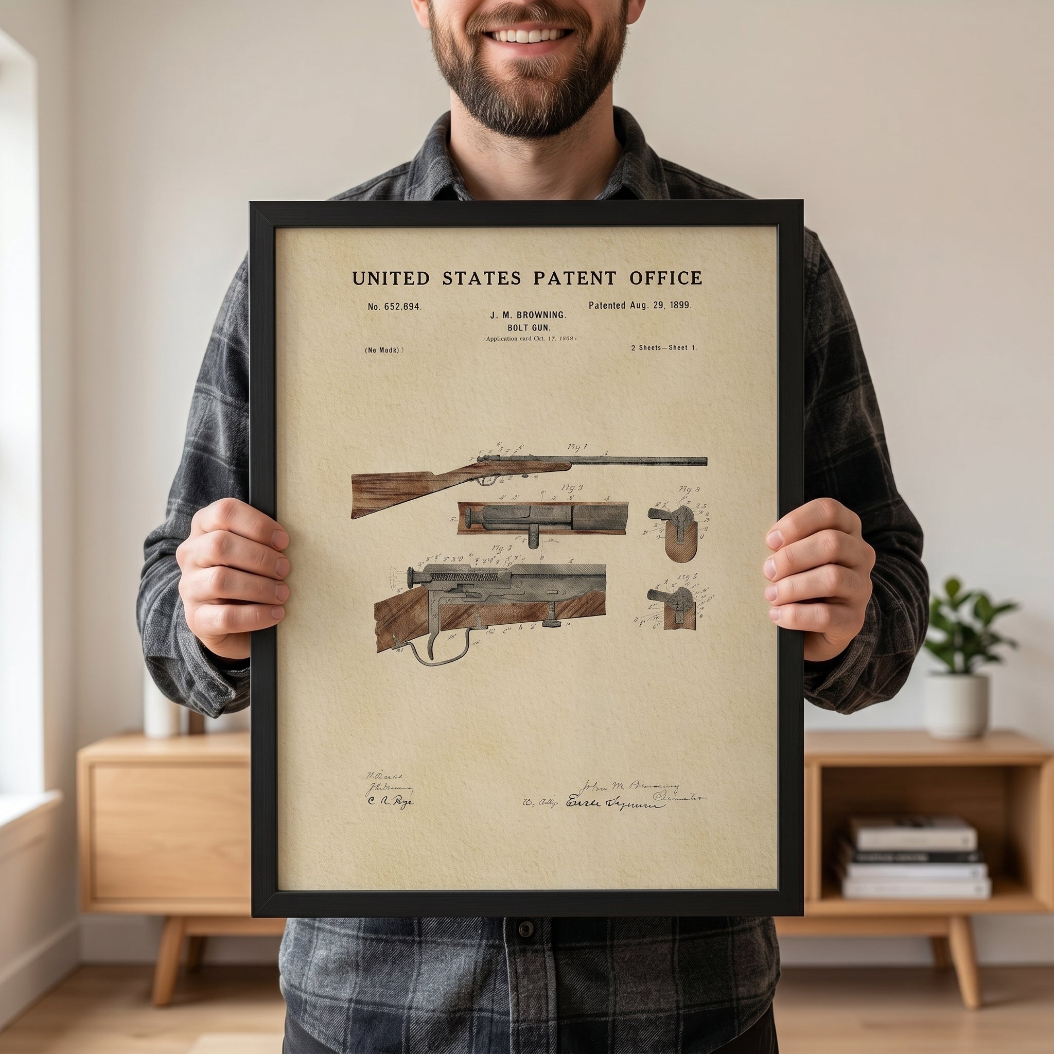 Person holding a large framed 1899 John M. Browning Hunting Rifle patent print to show scale.