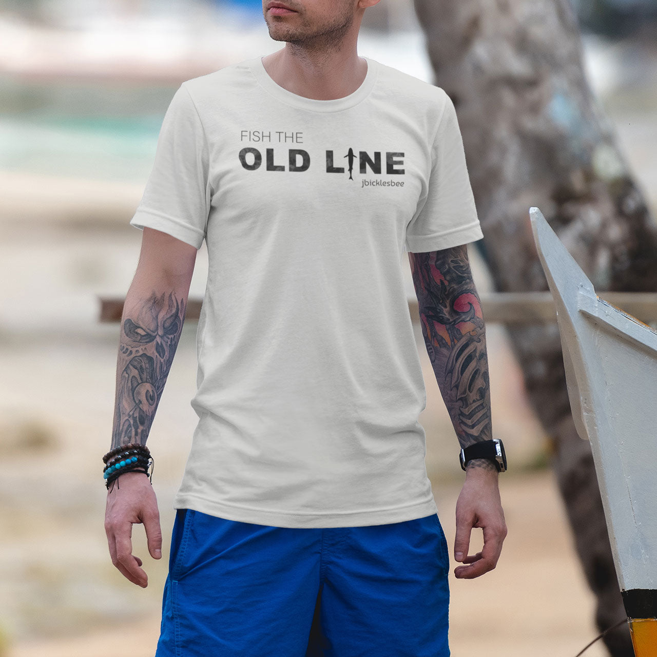 man wearing fish the old line t-shirt on the beach athletic heather