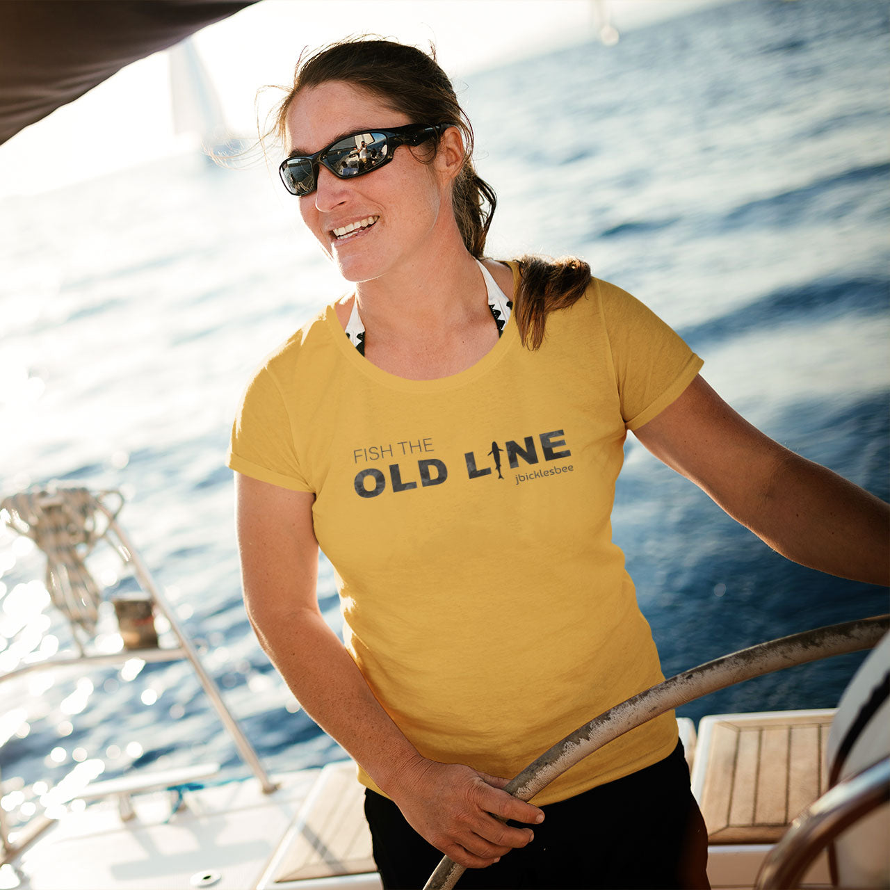 woman on a sailboat wearing OLD LINE Maryland Fishing T-shirt mustard